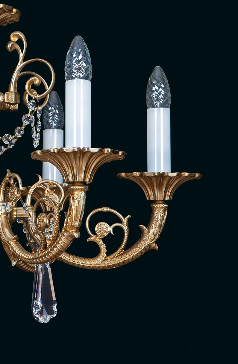 Détail d'une branche recourbée en laiton avec coupelle festonnée et fausse bougie surmontée d'un verre.