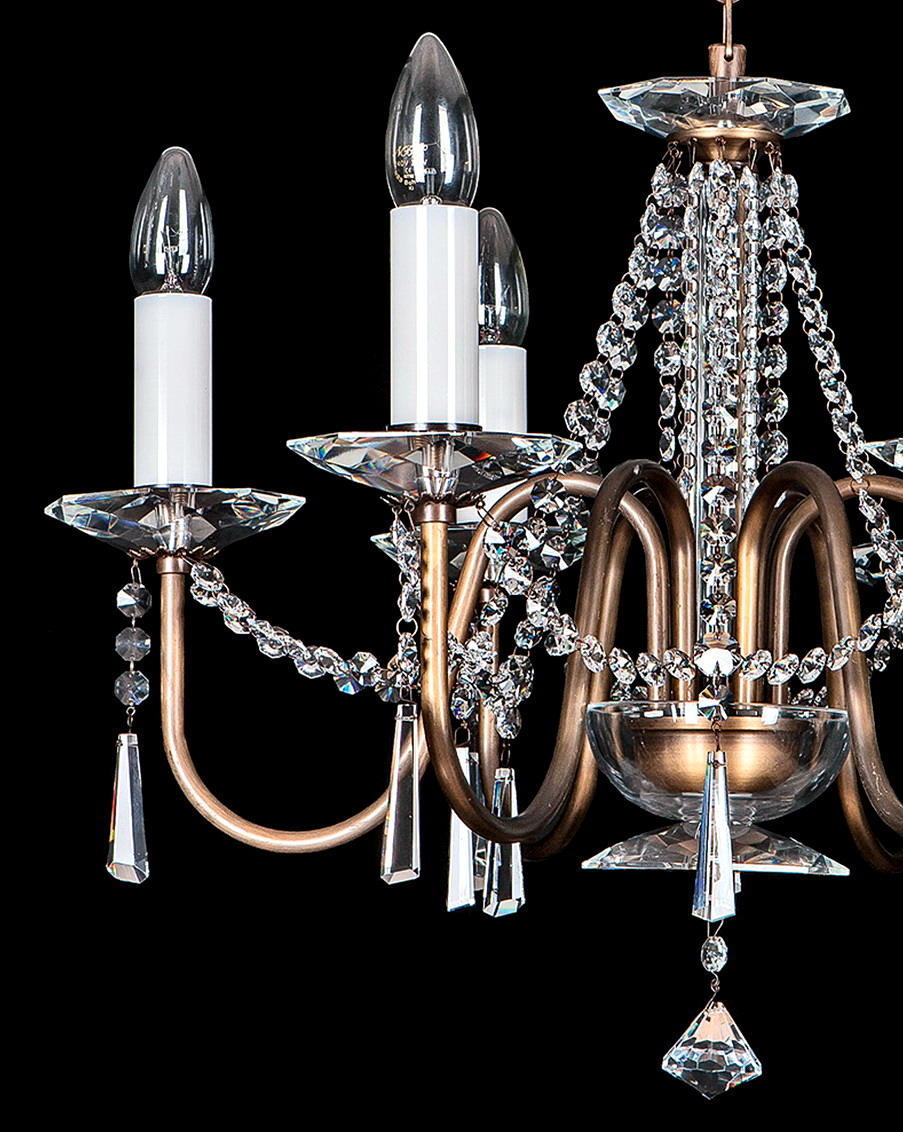 Gros plan sur les bras incurvés, coupelles cristal et douilles blanches du luminaire