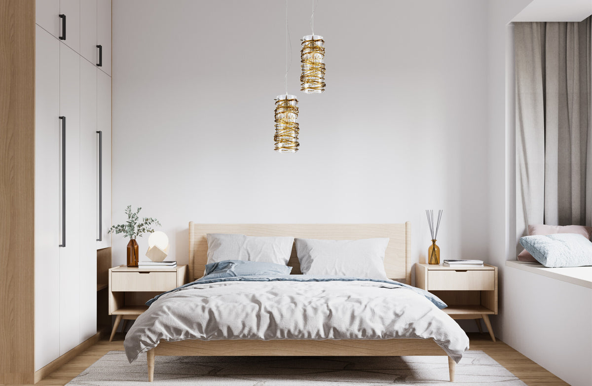 Deux suspensions cylindriques dorées suspendues au-dessus d'une chambre moderne à tête de lit en bois clair.