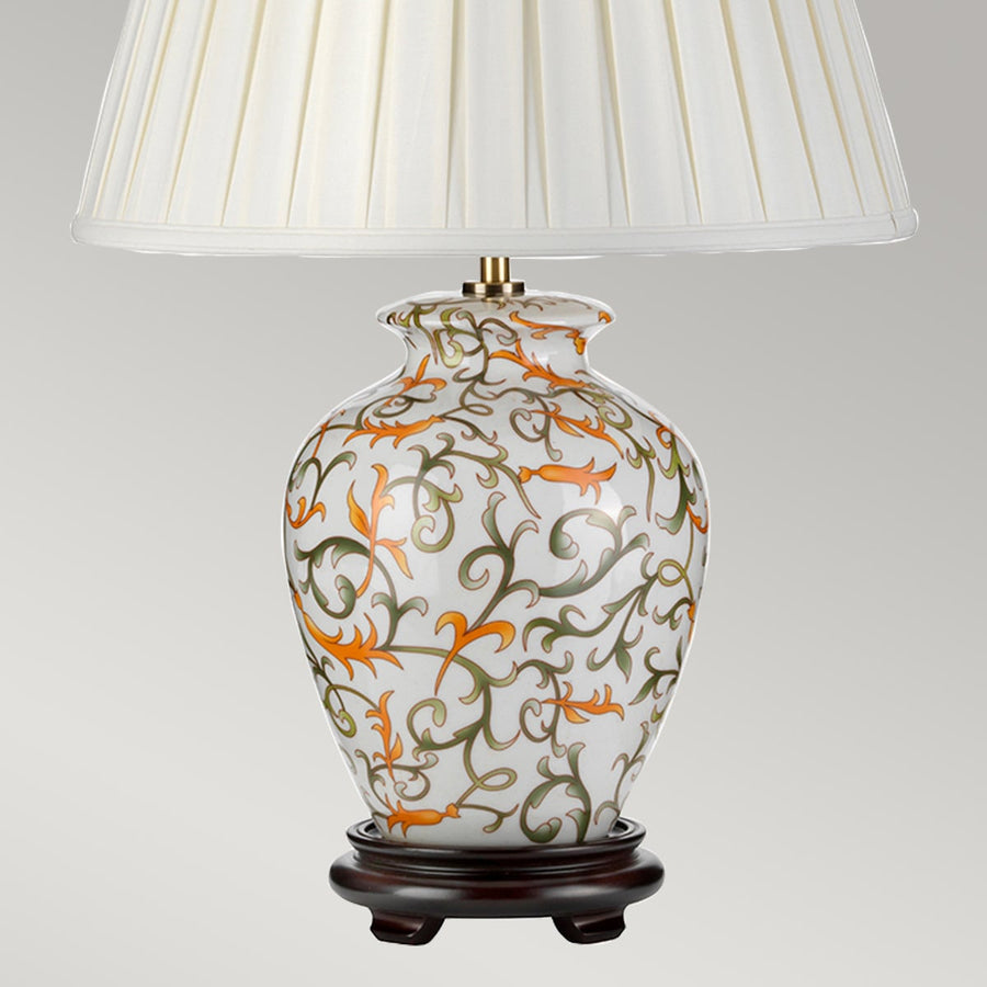 Détail du pied en céramique fleurie orange et vert, socle en bois foncé.