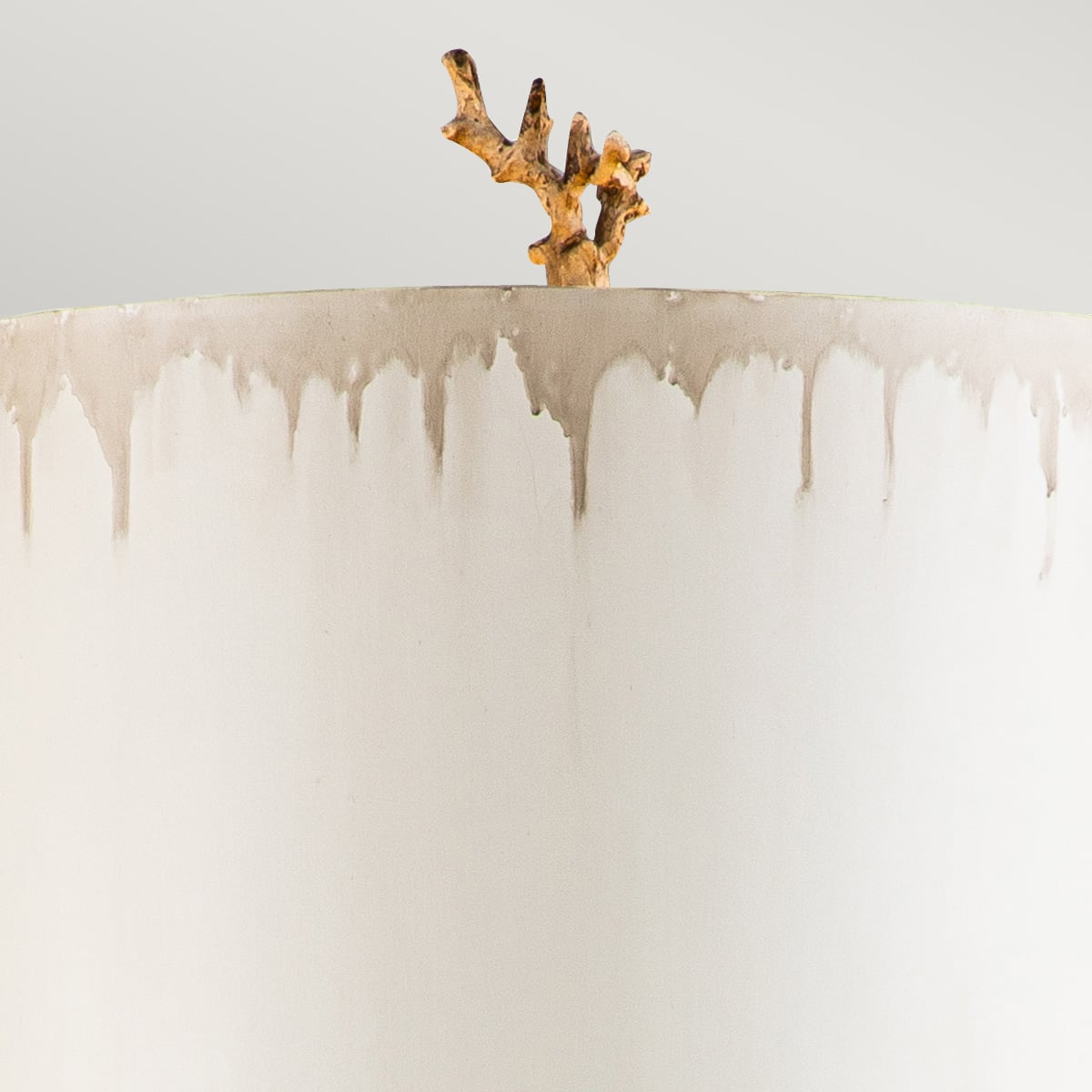 Détail du sommet avec branche dorée et coulures sur l'abat-jour blanc.