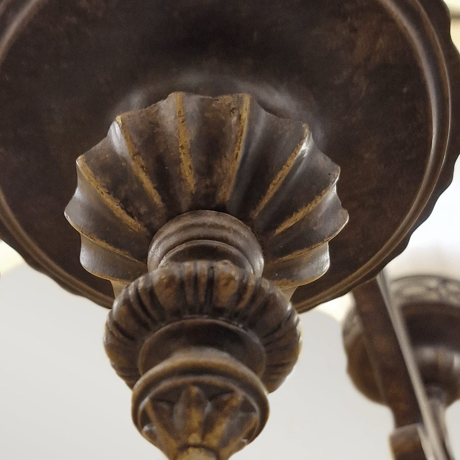Gros plan sur le fleuron inférieur en métal foncé aux reflets dorés