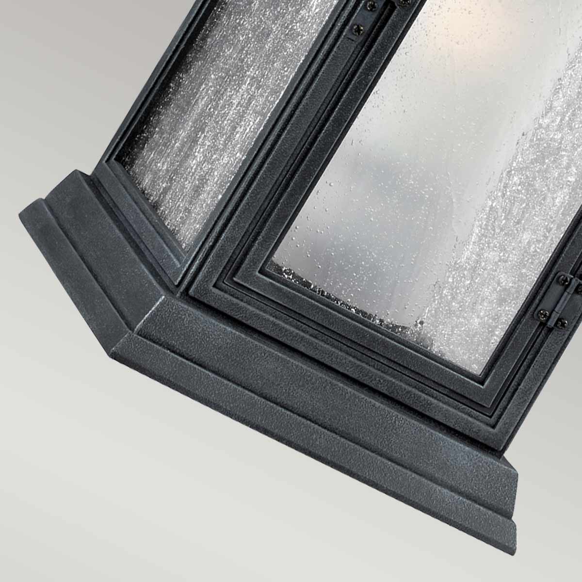 Détail du bas : socle mouluré noir et angle de la lanterne en verre.
