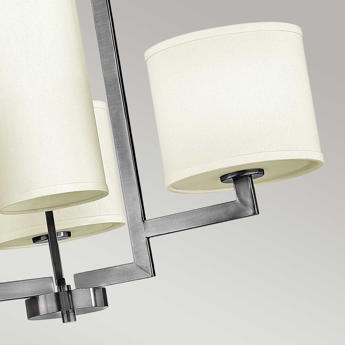 Détail d'un bras métallique supportant un abat-jour cylindrique en tissu clair