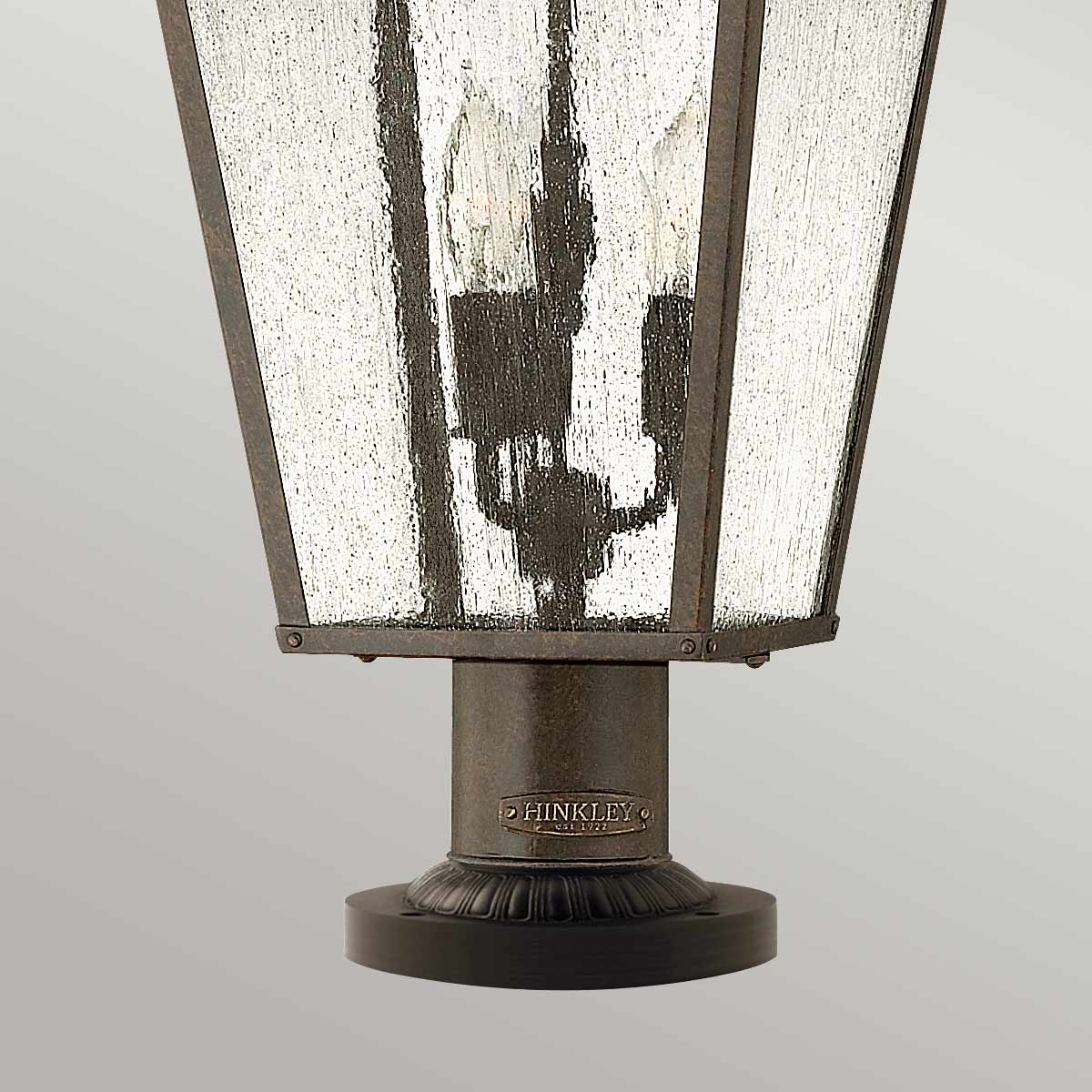 Gros plan sur la base cylindrique, bague ornée et socle circulaire du luminaire.
