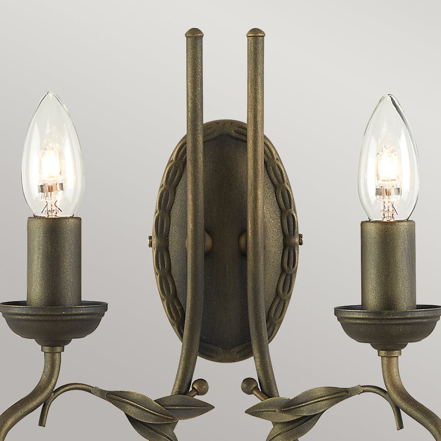 Gros plan sur la platine ovale tressée et les deux tiges verticales dorées.