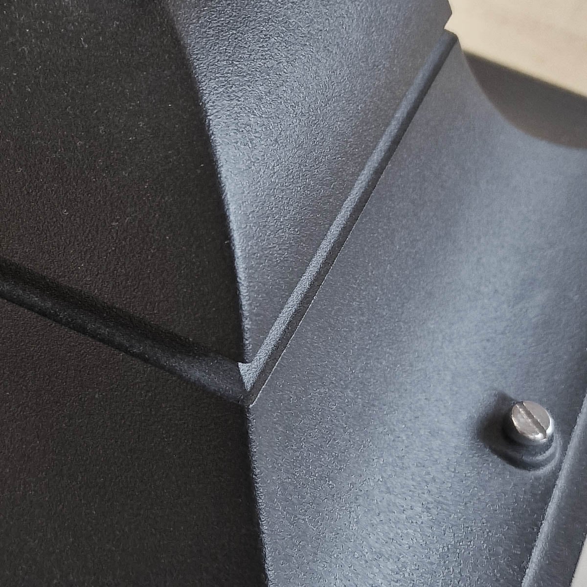 Gros plan sur la texture métallique noire et la vis de fixation du sommet