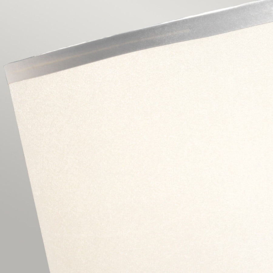 Gros plan sur la texture tissée de l'abat-jour gris et son liseré satiné