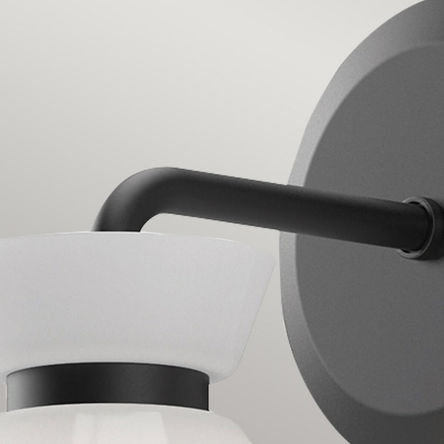 Détail du bras fixé à la platine murale ronde en métal noir mat.