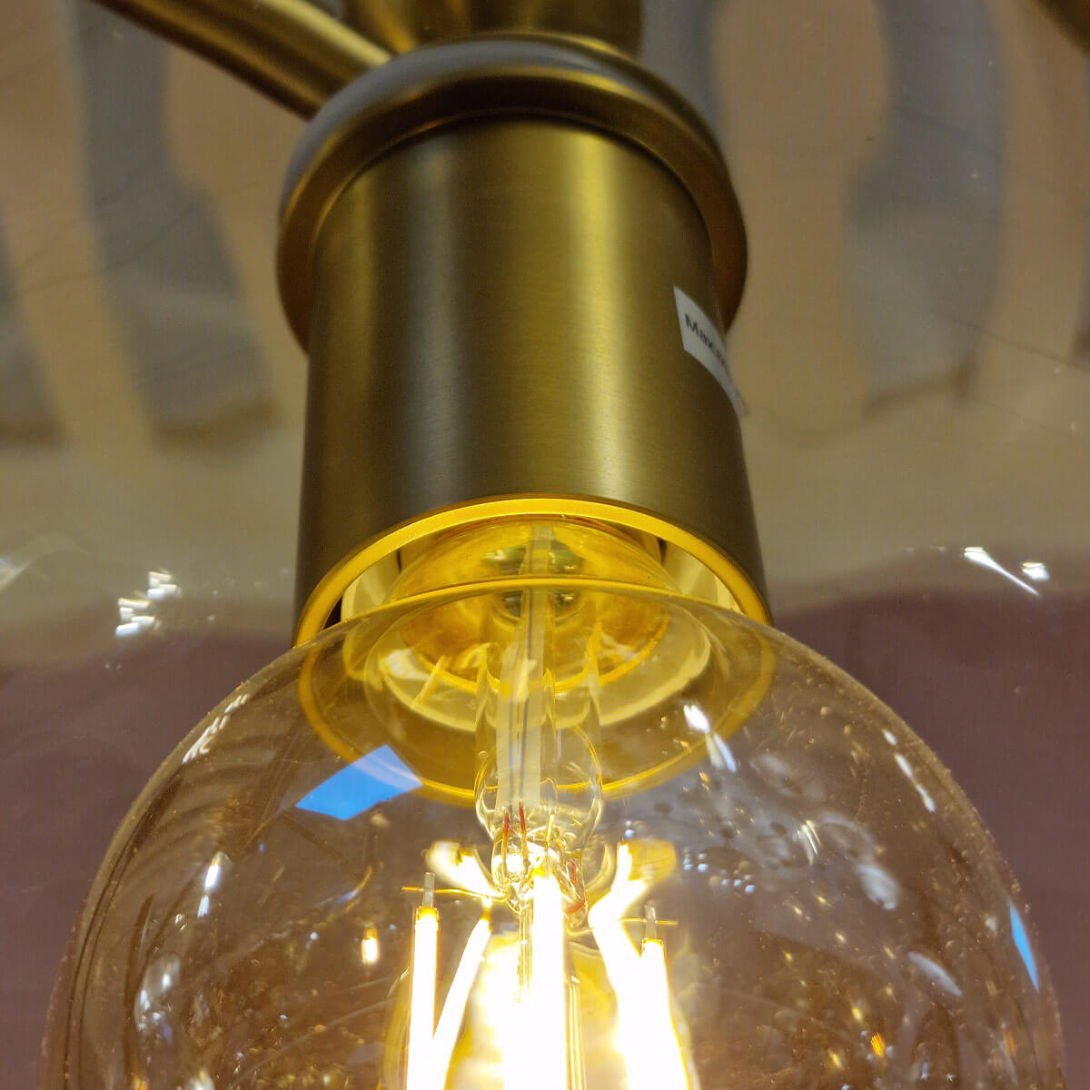 Vue rapprochée de la douille dorée tenant l'ampoule sous la cloche en verre