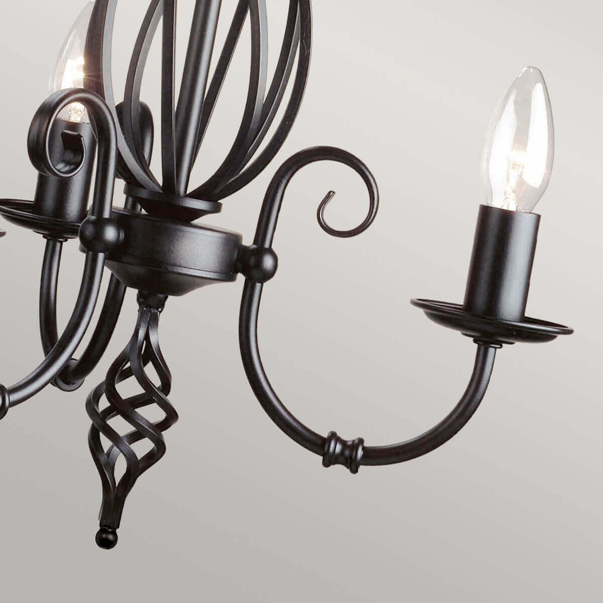 Vue rapprochée des trois bras, volutes décoratives et pointe torsadée du lustre