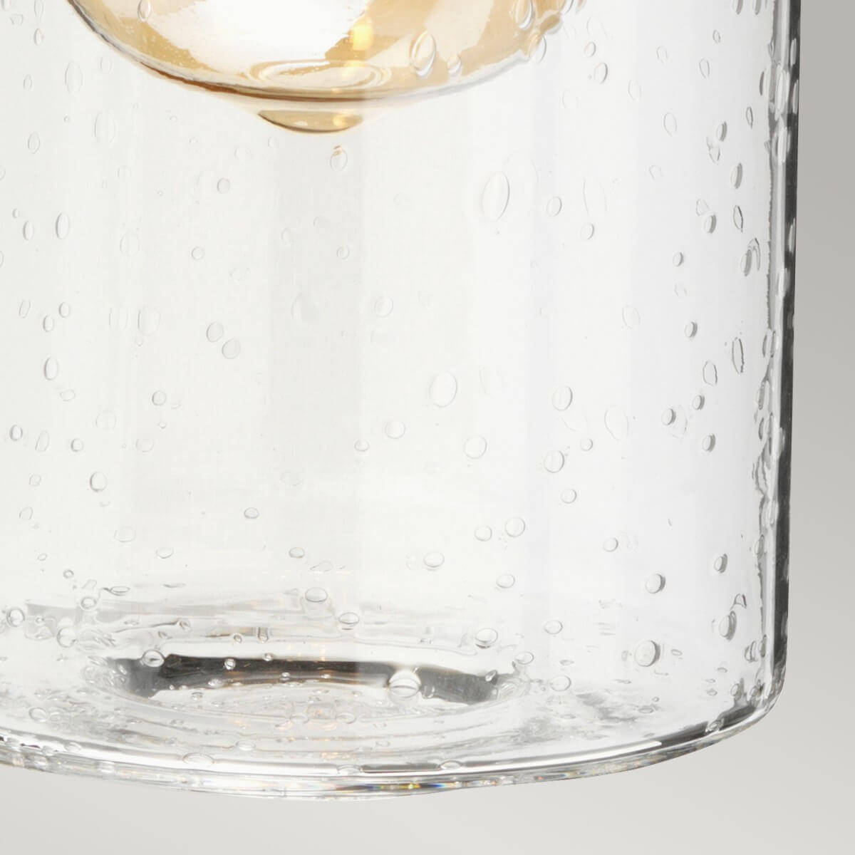 Détail du verre soufflé moucheté avec bulles d'air et reflets lumineux.