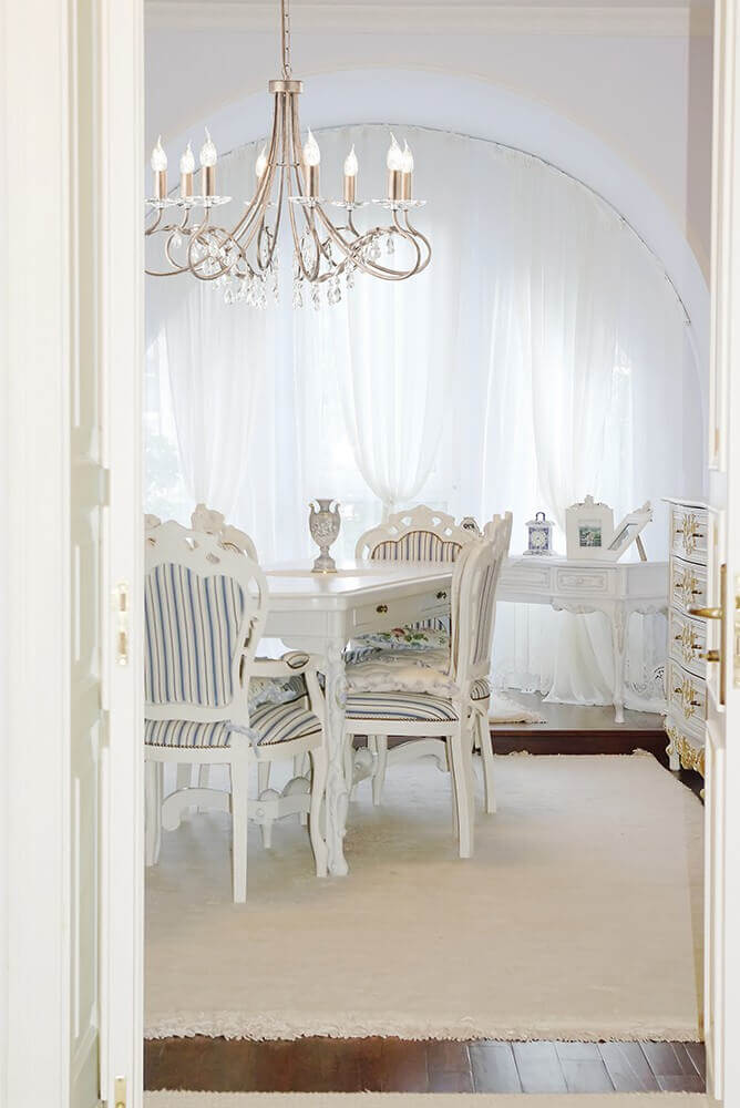 Lustre suspendu au-dessus d'une table de salle à manger blanche et chaises rayées.