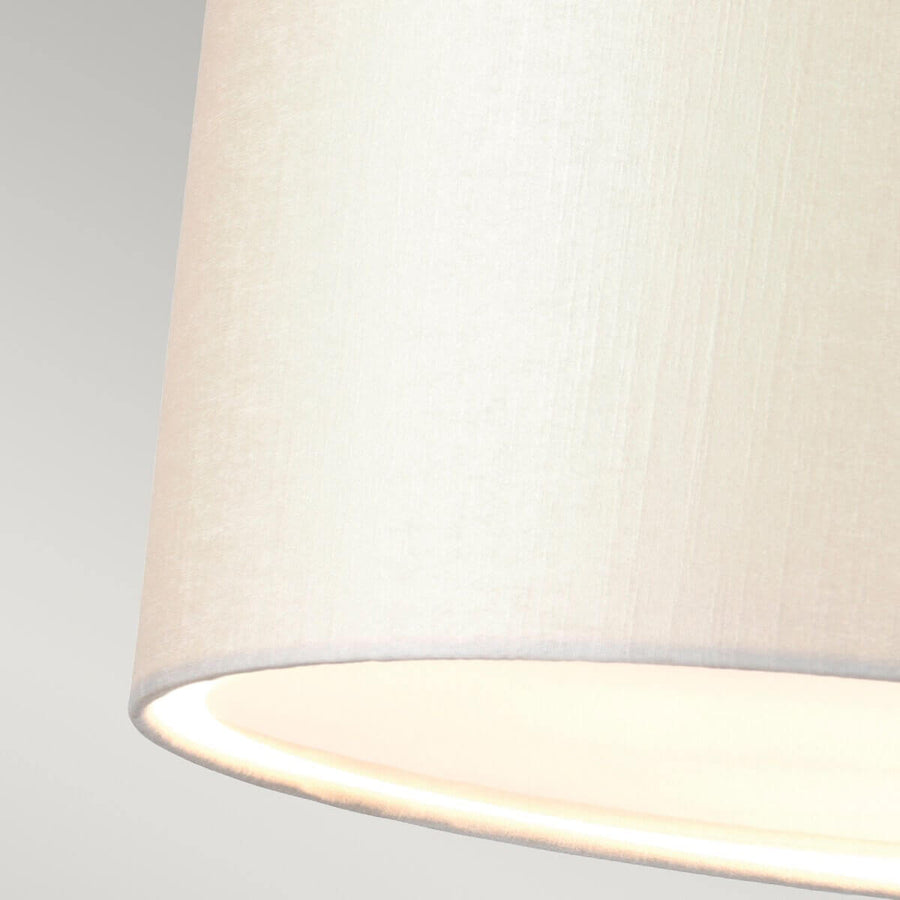 Détail gros plan de la texture tissu crème et bord inférieur éclairé.