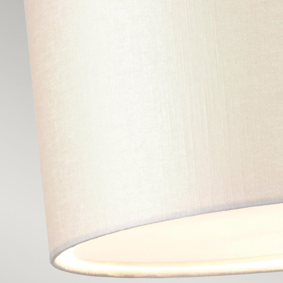 Gros plan sur la texture tissée de l'abat-jour crème et le diffuseur inférieur.