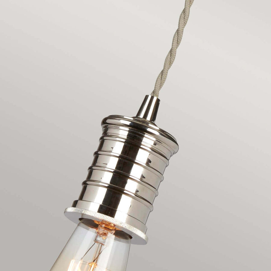Gros plan sur la douille cylindrique en nickel poli et l'ampoule à filament transparente.