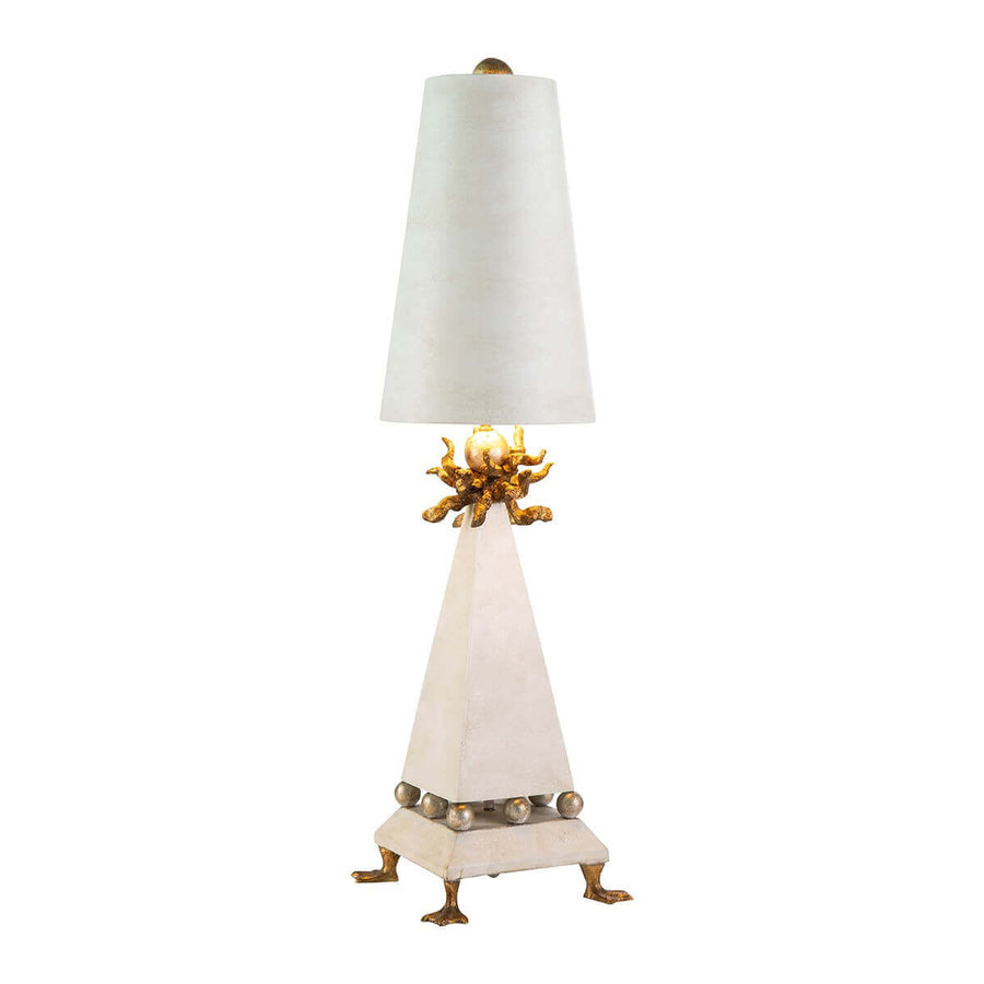 Lampe à poser de face sur fond blanc, abat-jour crème et base triangulaire dorée.