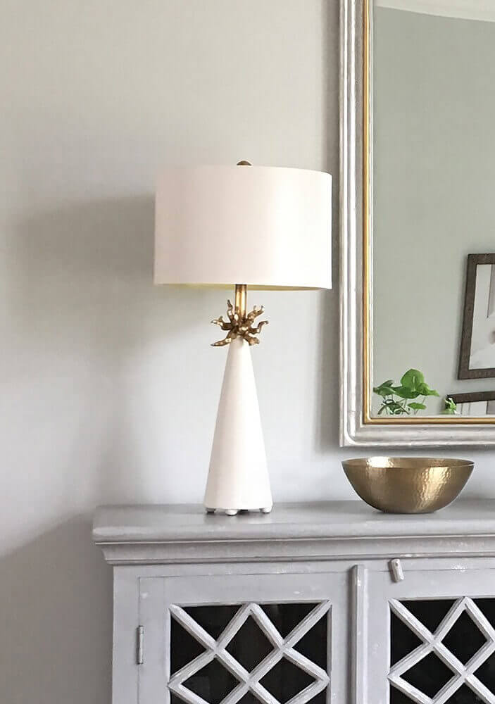 Mise en ambiance de la lampe posée sur un meuble gris devant un miroir