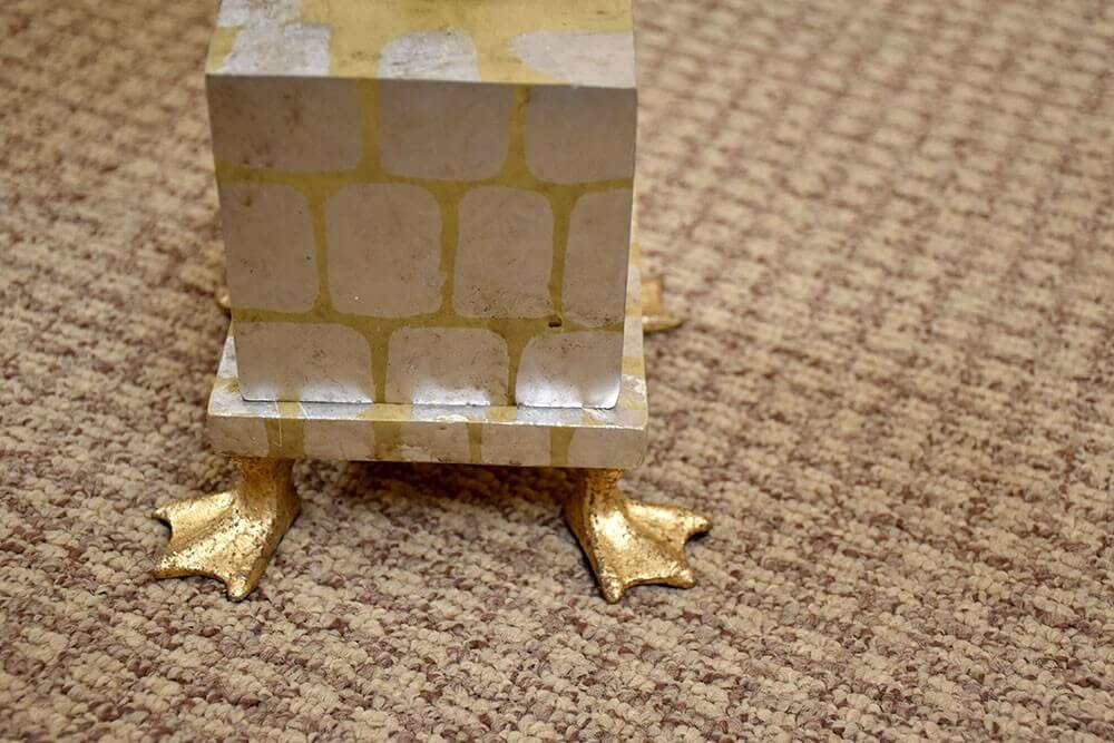 Détail du socle cubique imitant la brique, posé sur deux pieds dorés