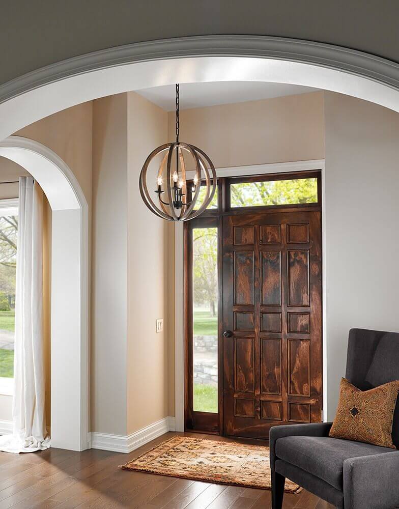 Suspension globe en bois installée dans une entrée devant une porte en bois.