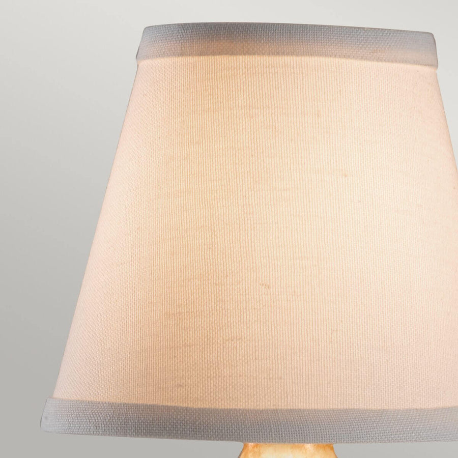Gros plan sur l'abat-jour en tissu beige avec liseré gris en haut et en bas