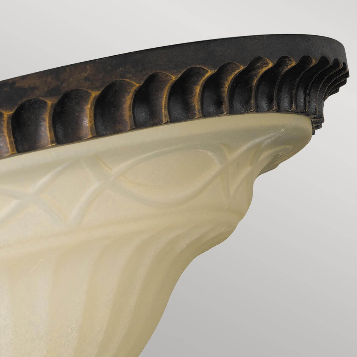Détail du bord godronné en métal patiné doré et du verre moulé à motifs géométriques