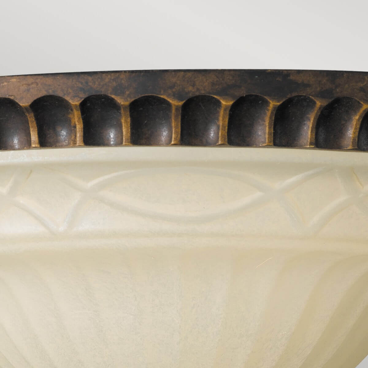 Gros plan sur la frise décorative du cerclage bronze surmontant la coupelle en verre ivoire