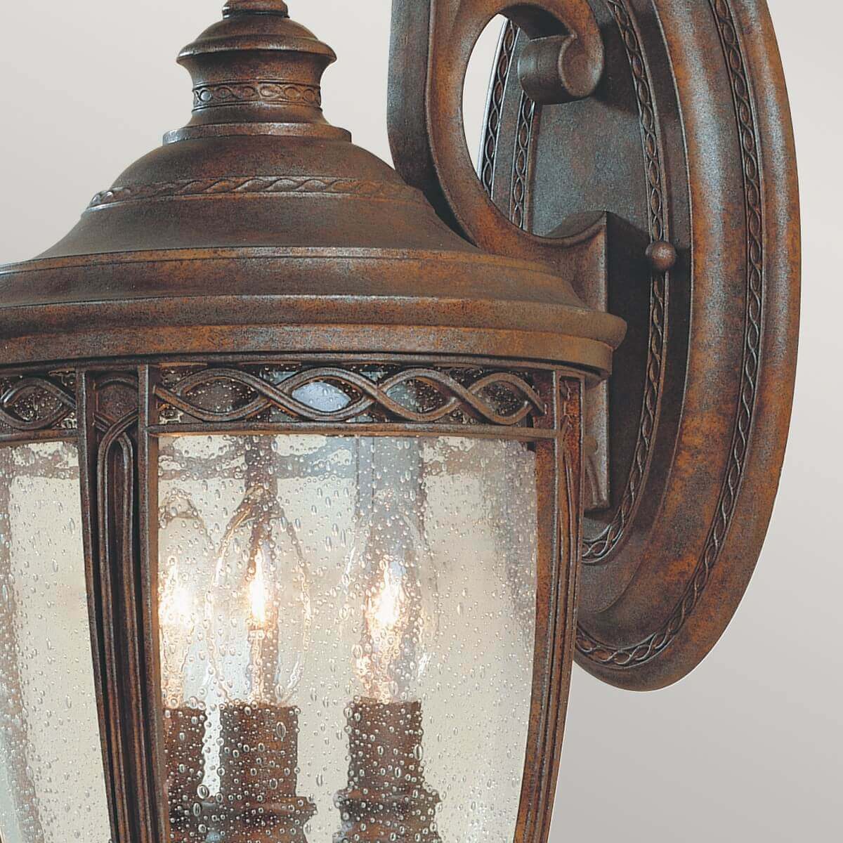 Détail du bras sculpté et de la verrière mouillée, finition bronze vieilli et décor tressé.