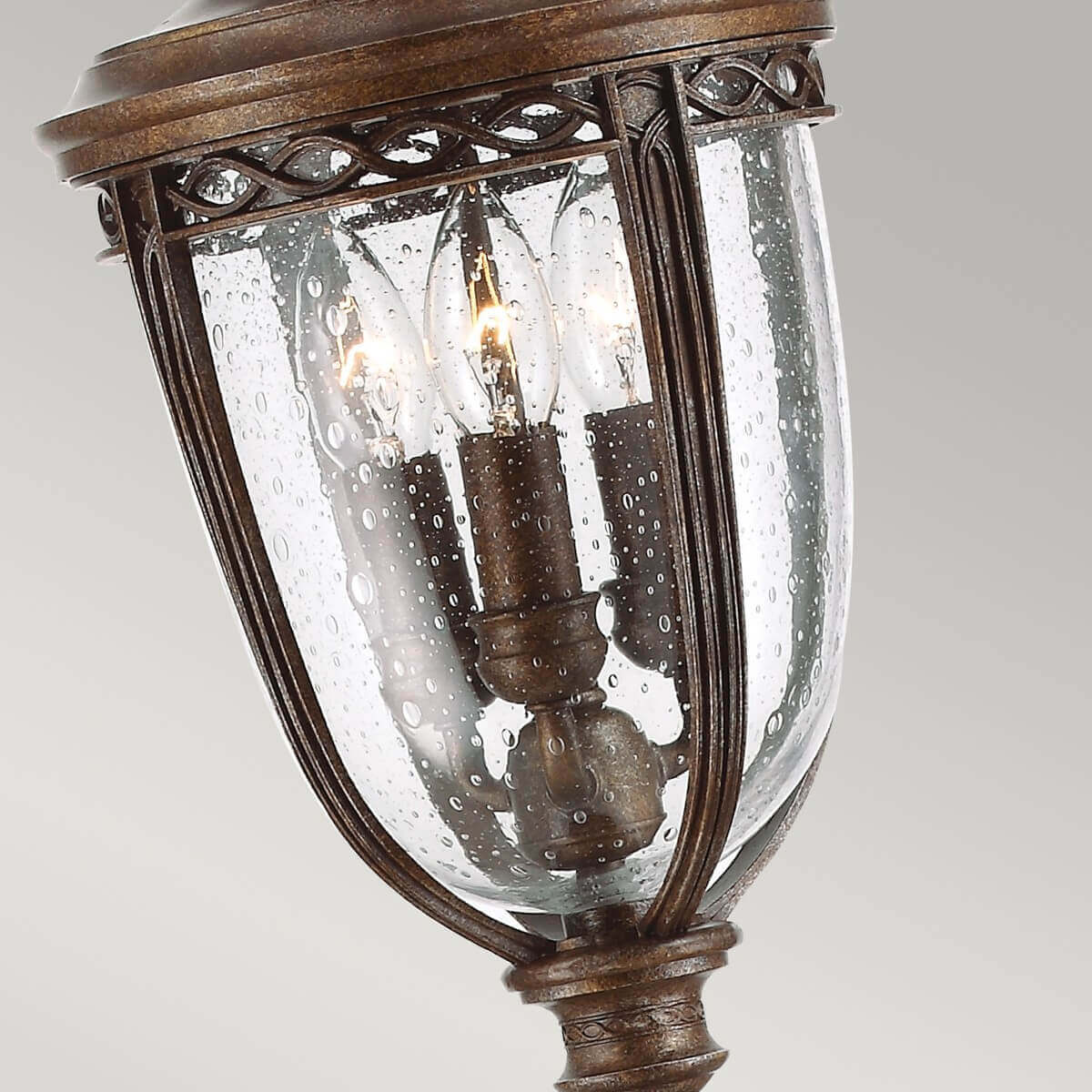 Gros plan du bas de la lanterne, verre gouttelettes et trois ampoules à flamme visibles.