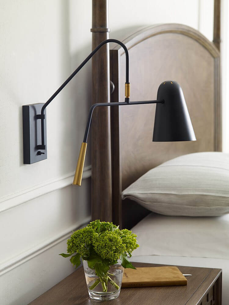 Ambiance de chevet avec bouquet vert sur table de nuit et lampe murale noire