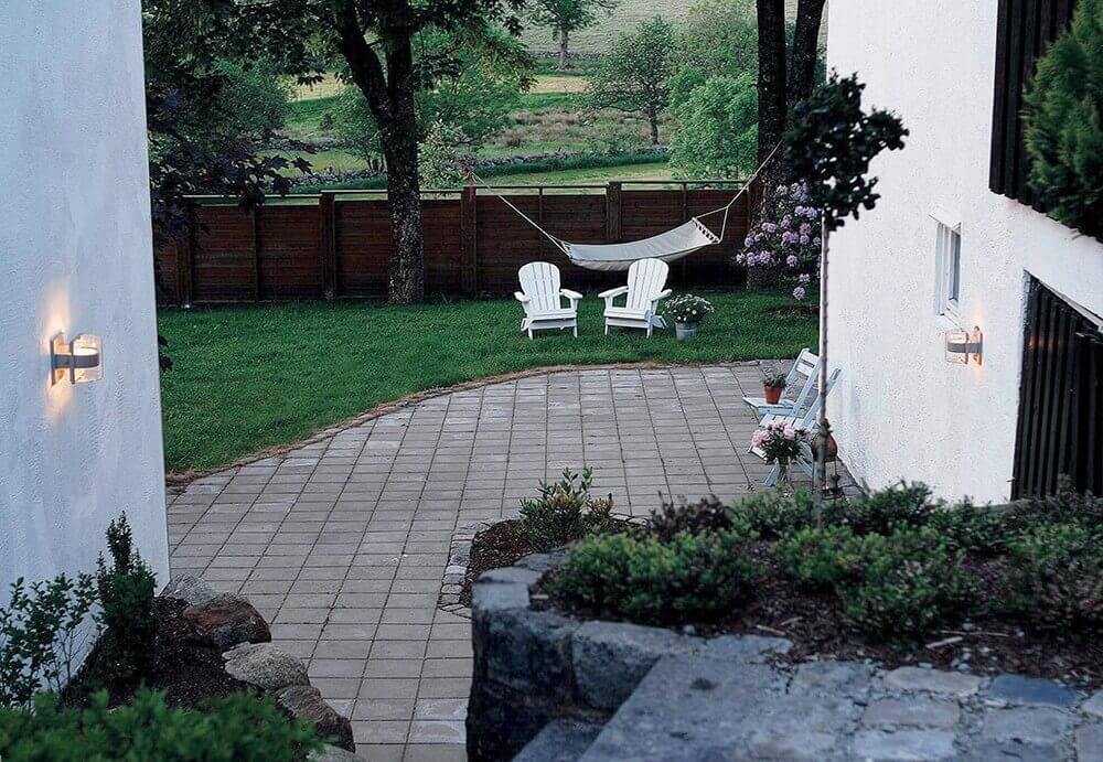 Mise en ambiance extérieure, deux appliques murales éclairant une terrasse et un jardin.