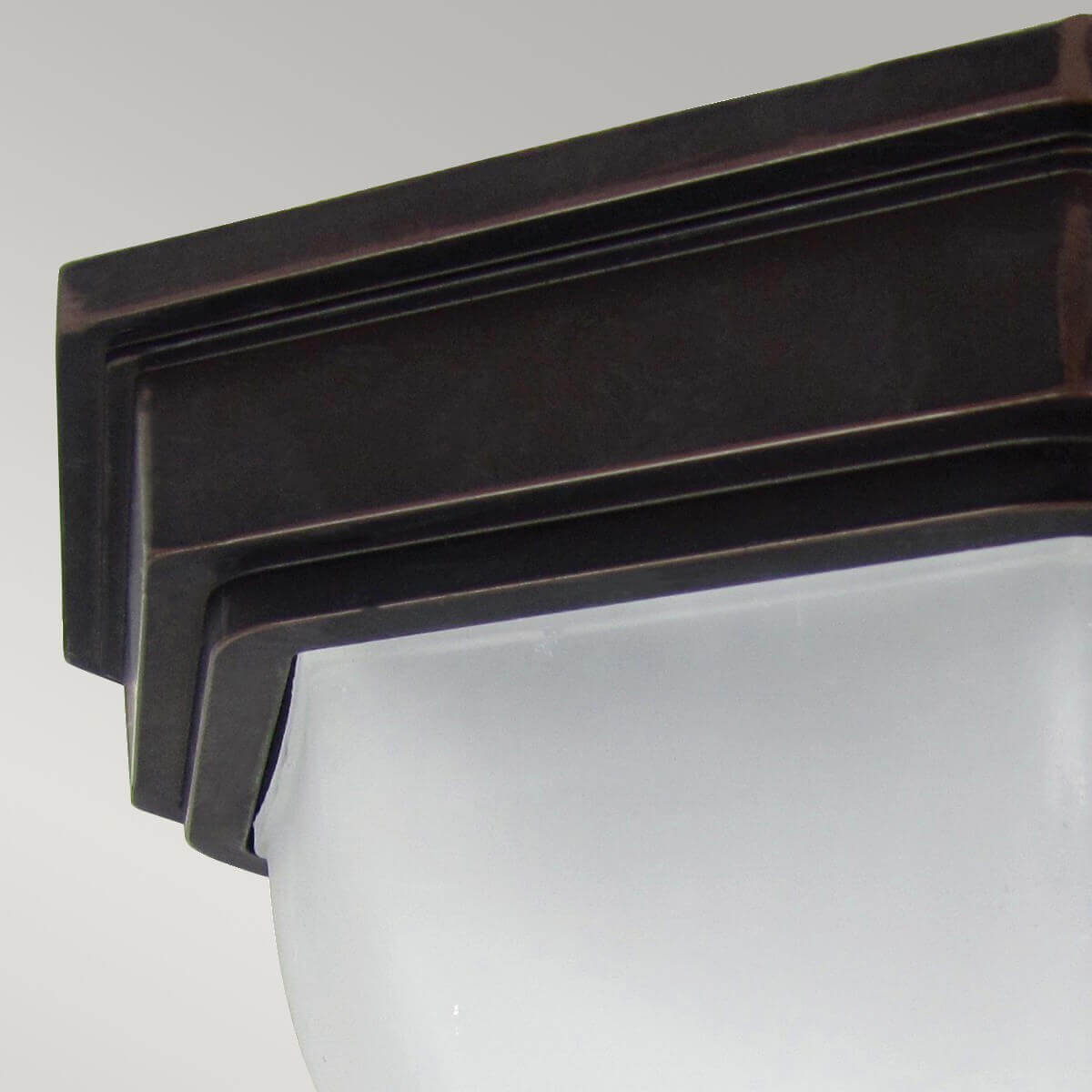 Détail de la finition bronze et du bord mouluré maintenant le verre dépoli