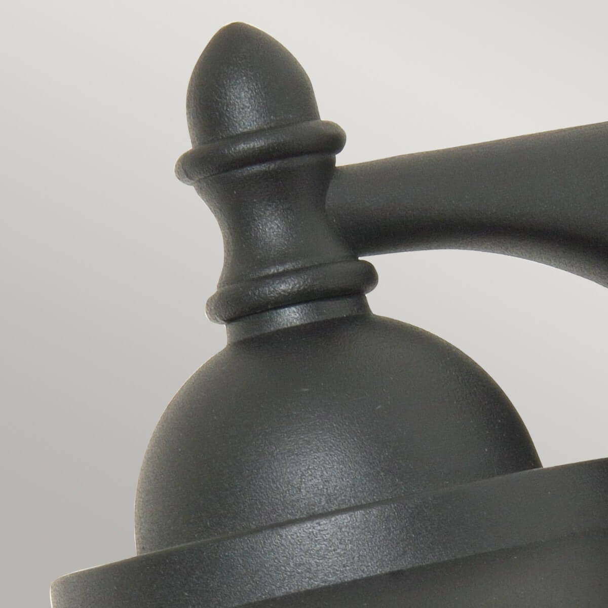 Gros plan sur le bouton décoratif et le dôme supérieur de l'applique noire.