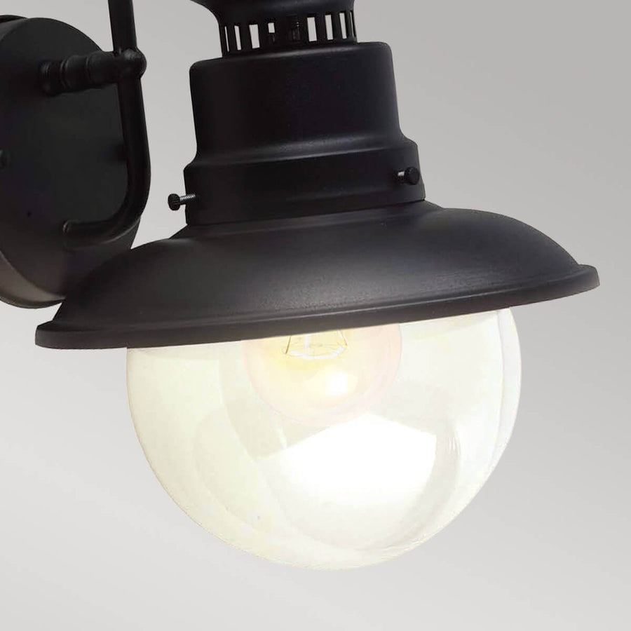 Détail rapproché du globe en verre éclairé, ampoule visible sous l'abat-jour noir