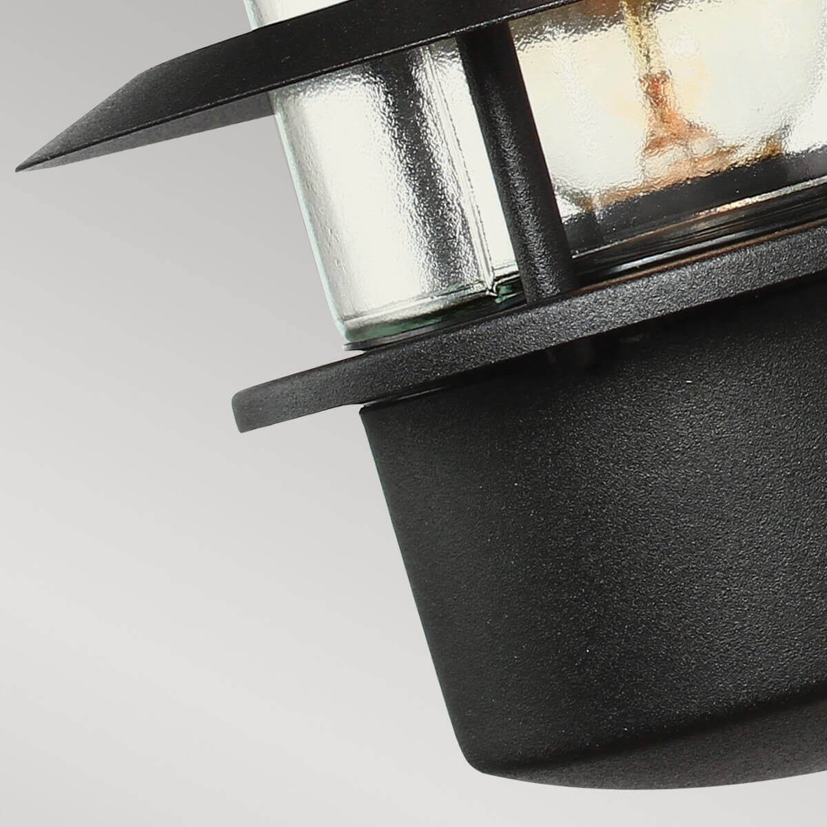 Gros plan du bas du luminaire, verre strié et collerette métallique noire