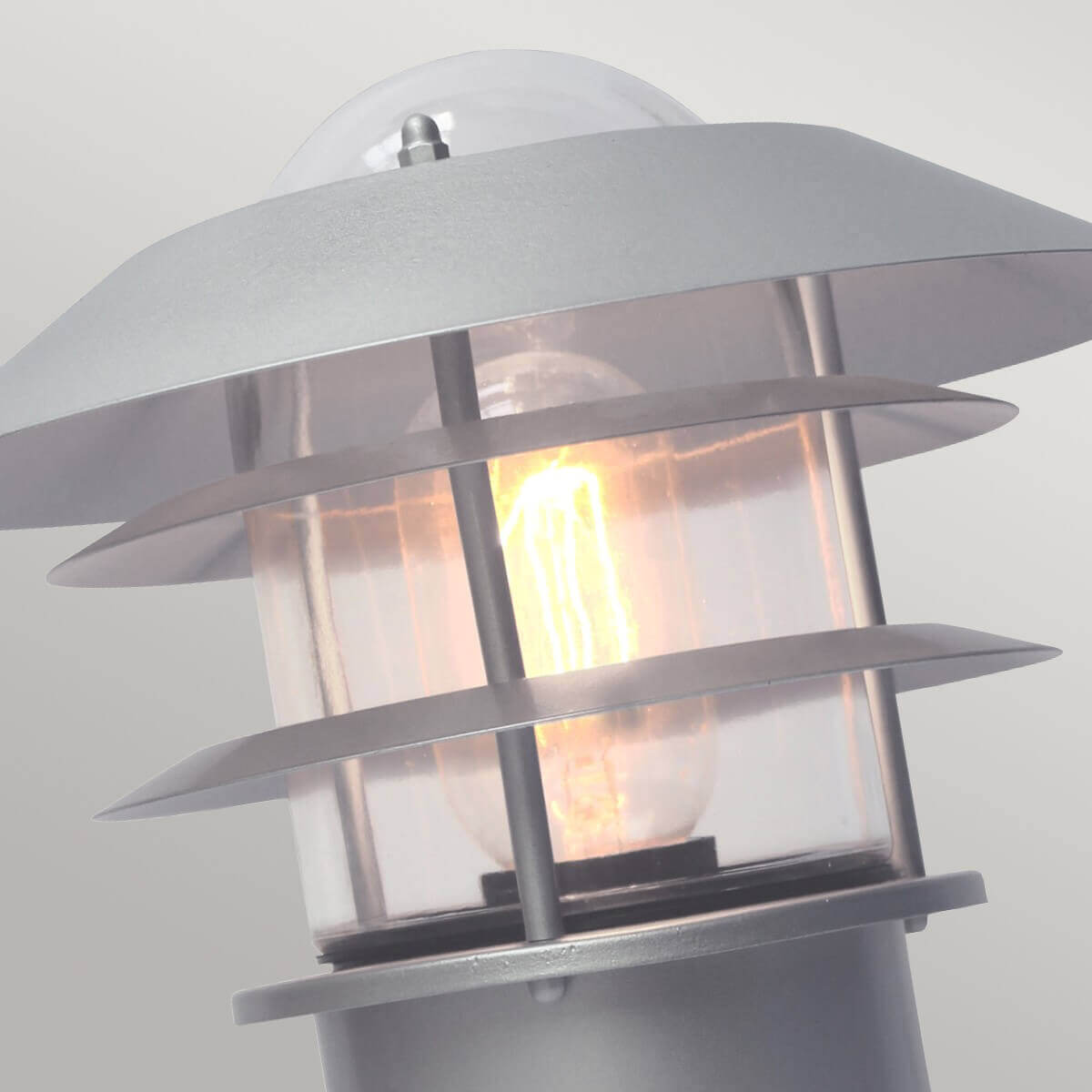 Gros plan sur la tête lumineuse, ailettes métalliques et ampoule filament allumée
