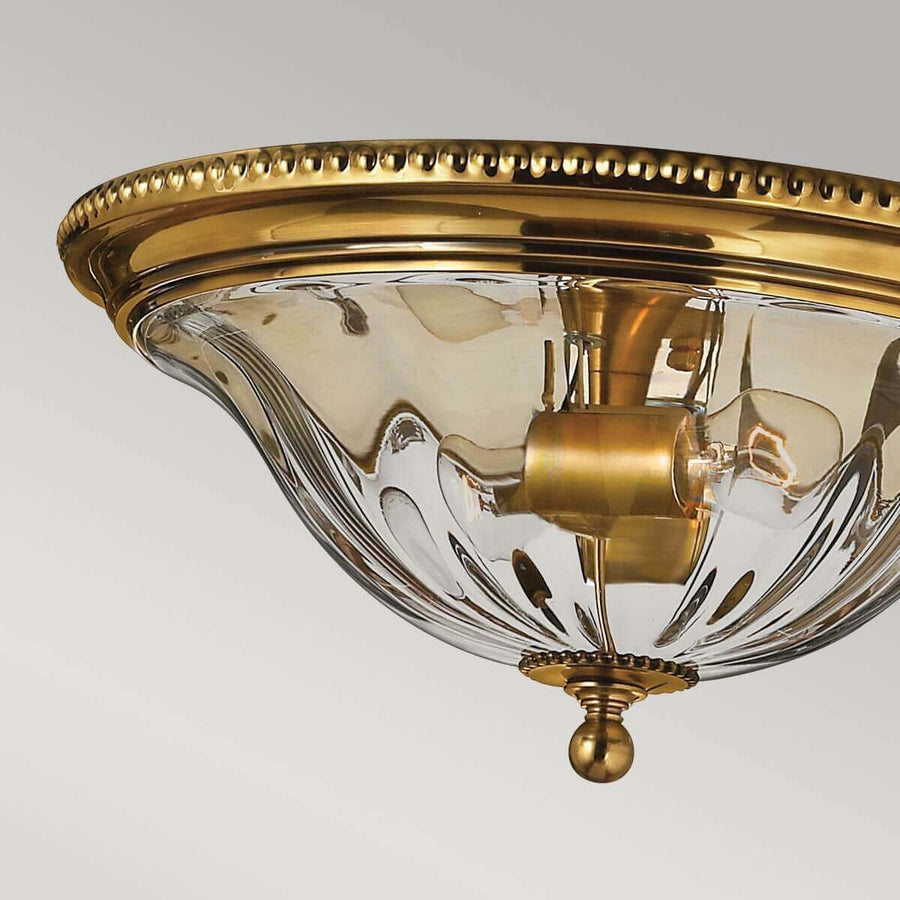 Détail du bord perlé en laiton brillant surplombant le verre godronné transparent