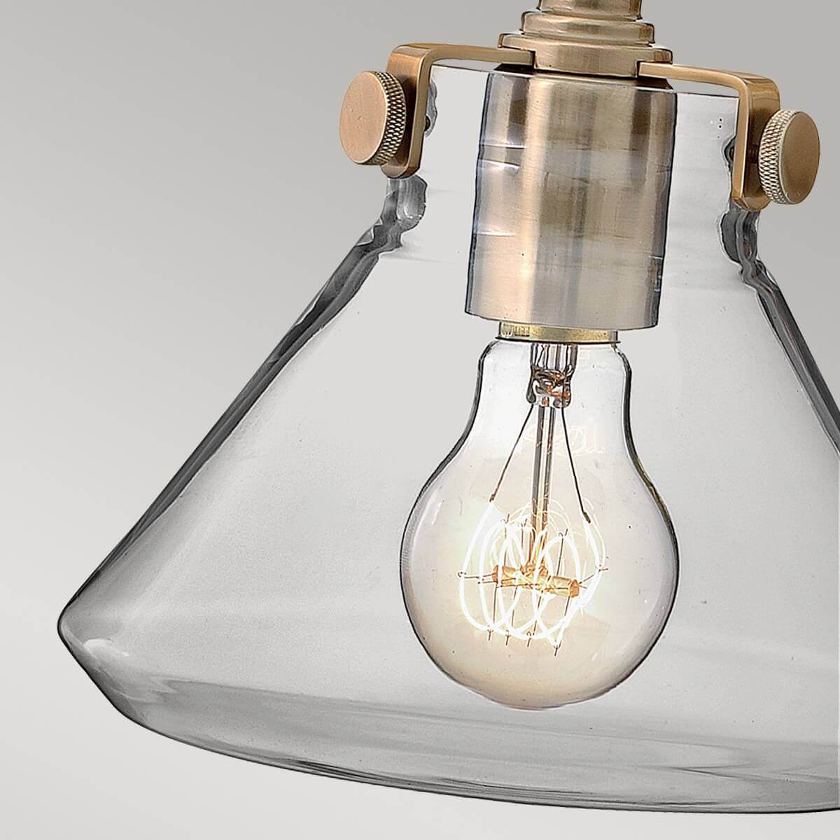 Gros plan du globe en verre transparent et ampoule à filament allumée