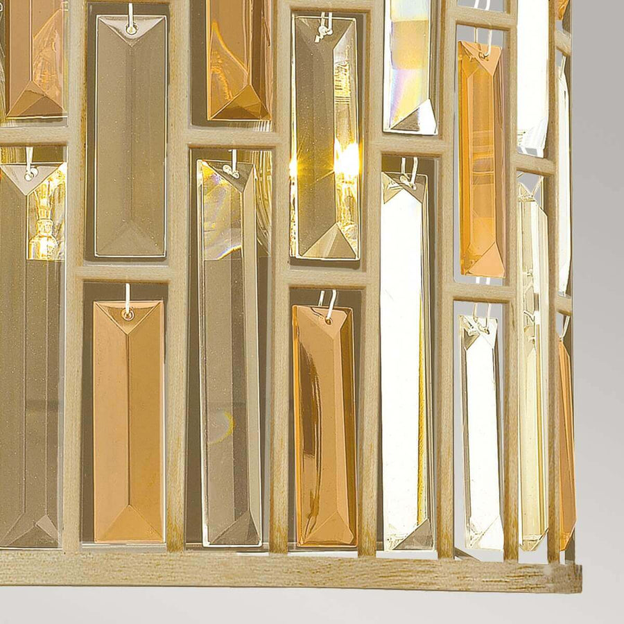 Gros plan sur la base, grille ajourée et pendentifs rectangulaires en cristal ambré.