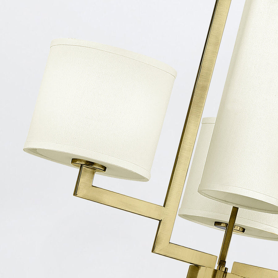 Détail d'un bras coudé et d'un abat-jour cylindrique blanc en tissu.
