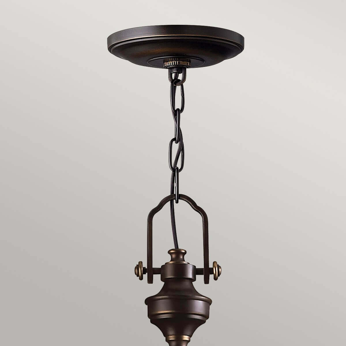 Gros plan sur la fixation au plafond, la chaîne et le sommet du luminaire en bronze.