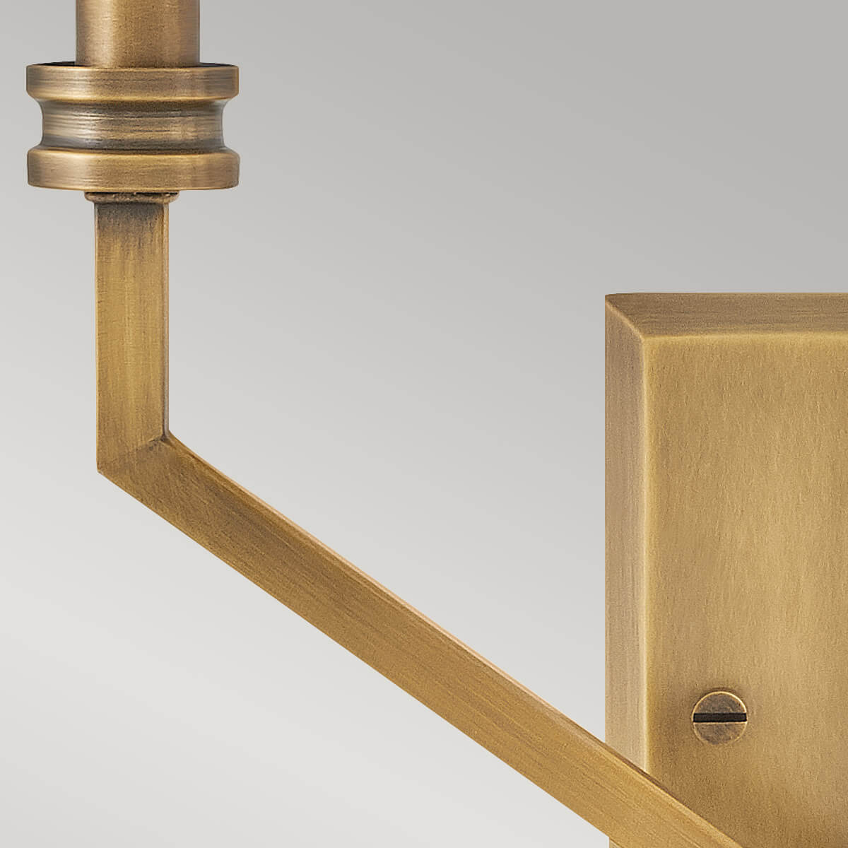 Détail du bras coudé et de la platine rectangulaire en laiton brossé avec vis.