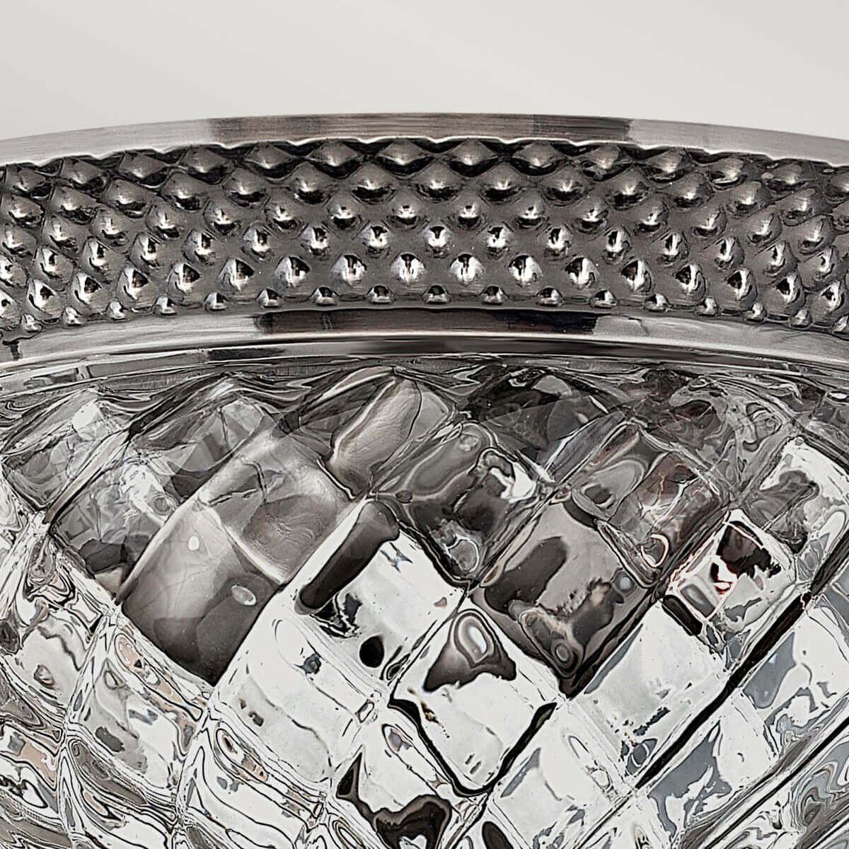 Détail du verre transparent à relief losangé reflétant la lumière sous la bordure ajourée