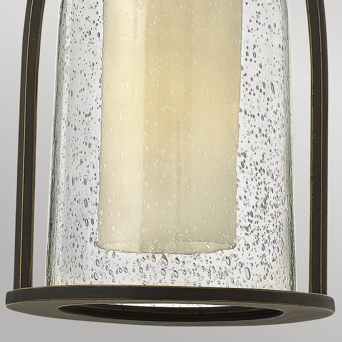 Gros plan du bas : verre granité, rebord circulaire et bordure bronze ajourée.