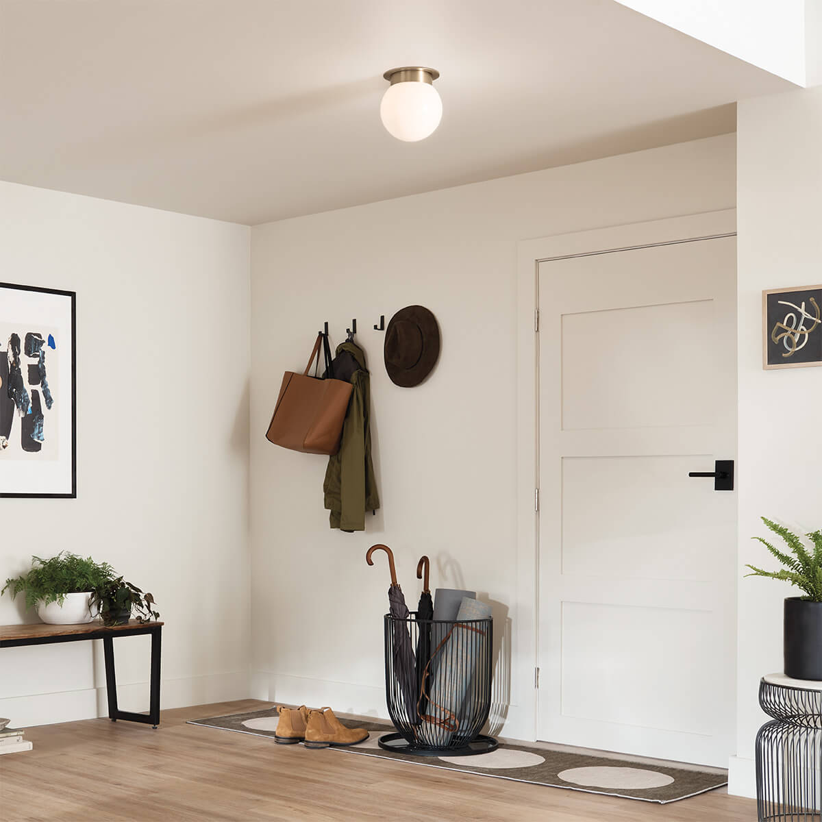 Mise en ambiance dans une entrée claire, plafonnier allumé au-dessus du portemanteau