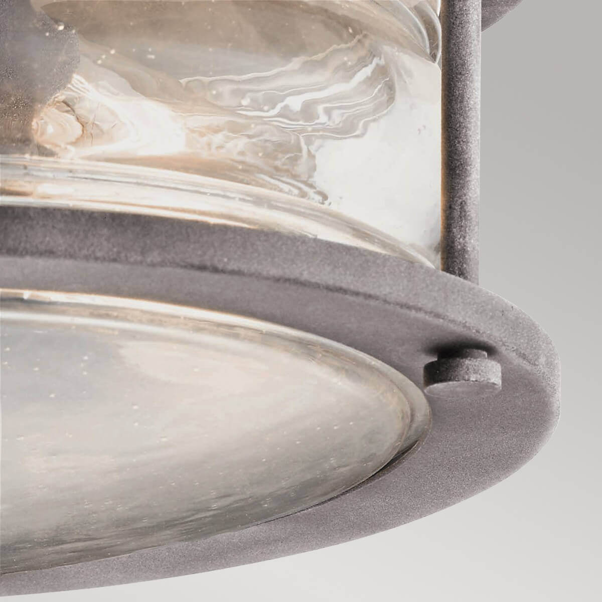 Gros plan sur la bague inférieure, le boulon et le verre bombé du plafonnier.