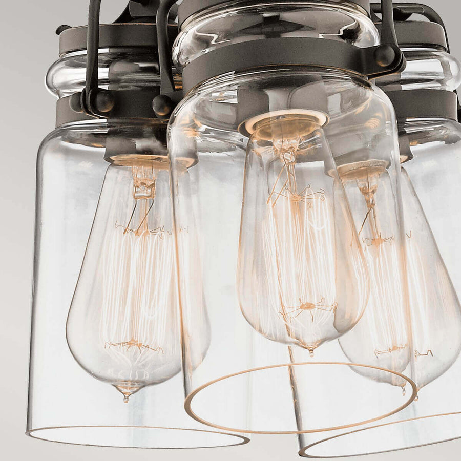 Gros plan sur les ampoules à filament doré placées dans les abat-jour en verre transparent.