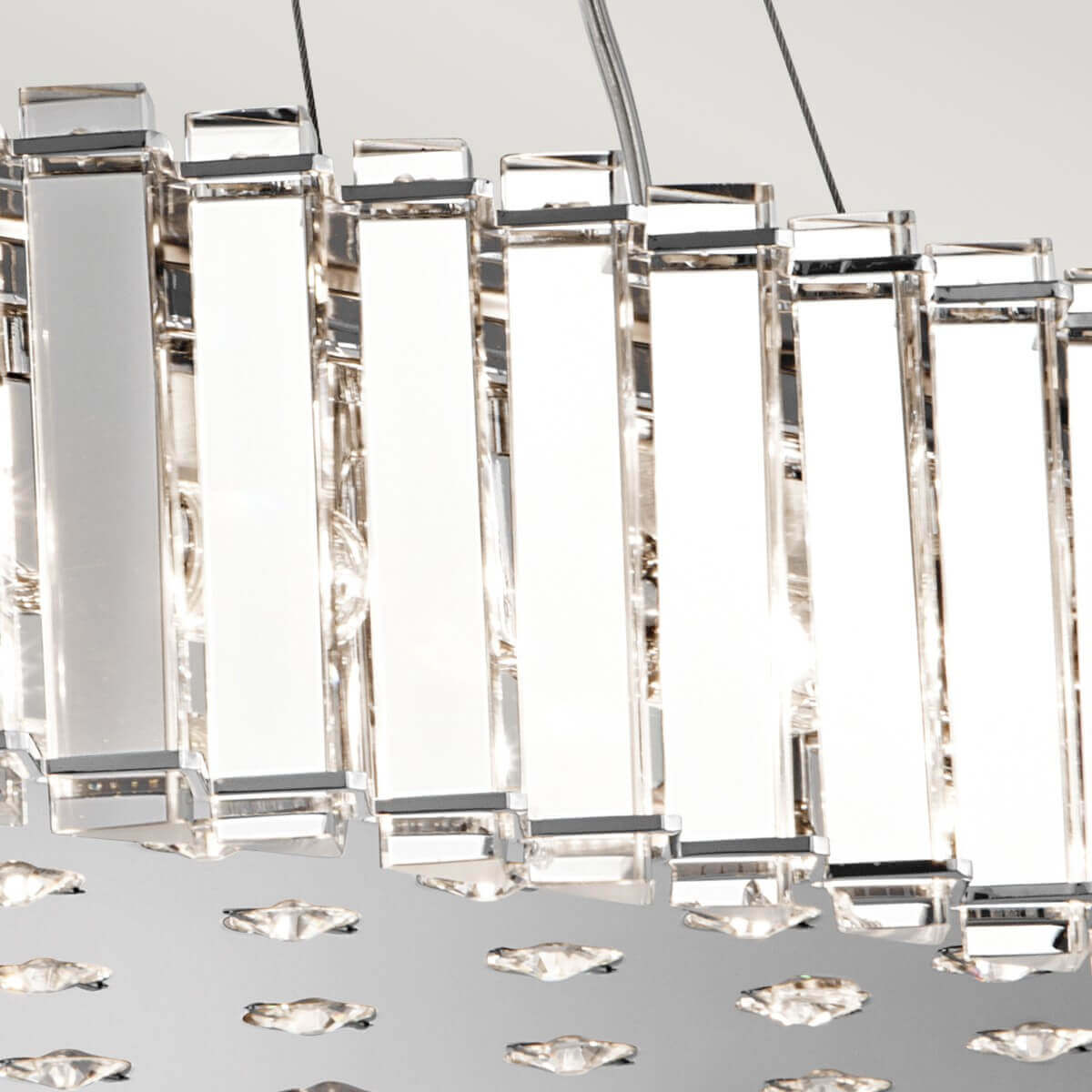 Détail des prismes de cristal taillés suspendus et de la plaque chromée ornée de losanges