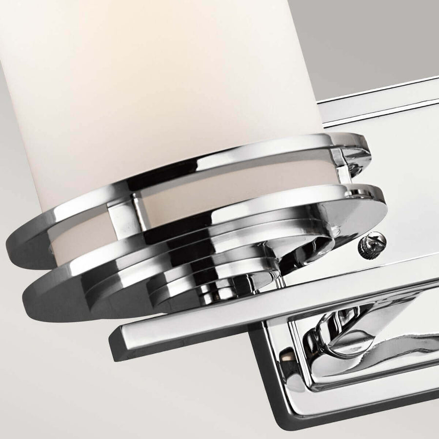 Gros plan sur la bague chromée maintenant le diffuseur cylindrique en verre opalin.
