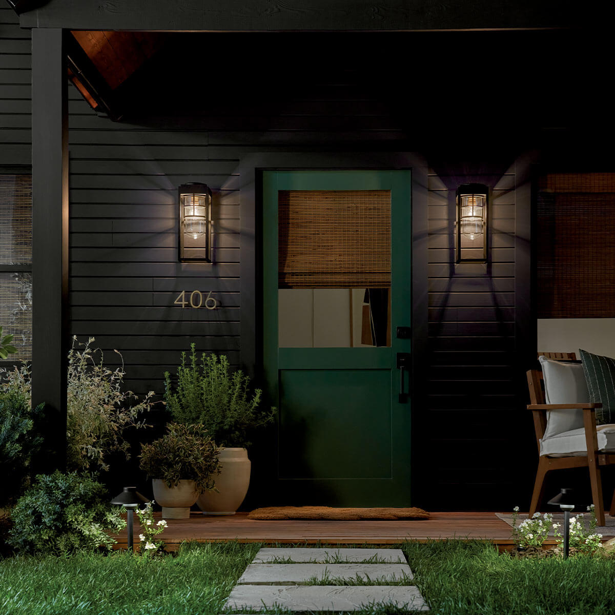 Mise en ambiance nocturne : deux appliques encadrant une porte verte de maison